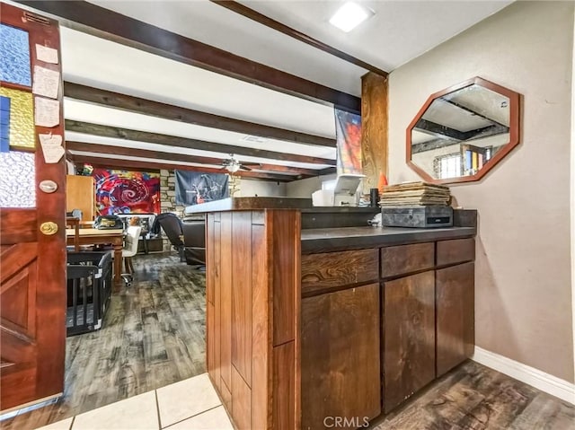 bar featuring dark wood finished floors, beamed ceiling, baseboards, and ceiling fan