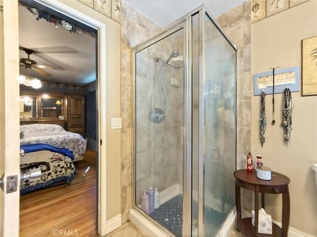 ensuite bathroom with a ceiling fan, a shower stall, ensuite bath, and wood finished floors