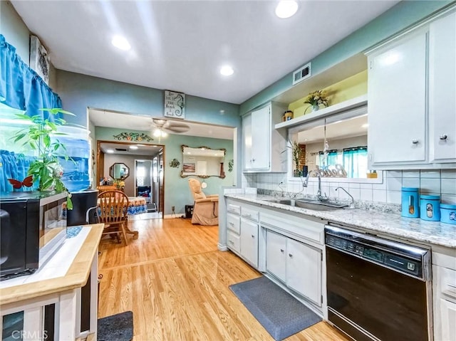 kitchen featuring a sink, visible vents, light wood-style floors, black dishwasher, and tasteful backsplash