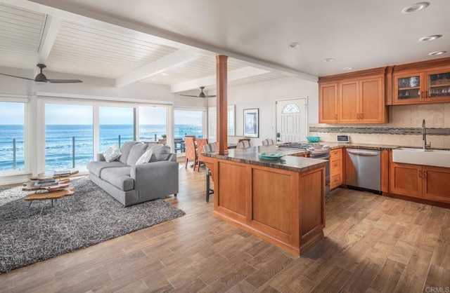 kitchen with stainless steel appliances, a water view, glass insert cabinets, a sink, and ceiling fan