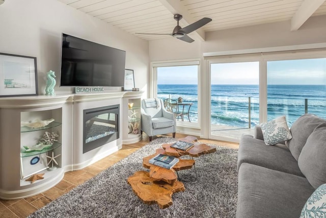 living room with a glass covered fireplace, wooden ceiling, ceiling fan, beamed ceiling, and wood tiled floor