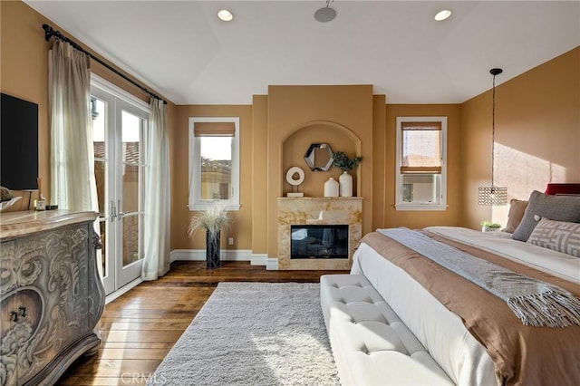 bedroom featuring recessed lighting, baseboards, dark wood-type flooring, and a glass covered fireplace