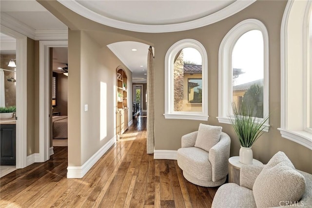 living area featuring hardwood / wood-style flooring, baseboards, and crown molding