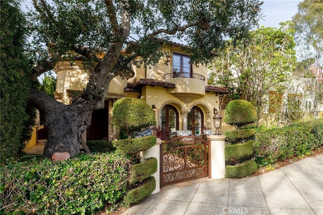 mediterranean / spanish house with a gate, a tile roof, and stucco siding