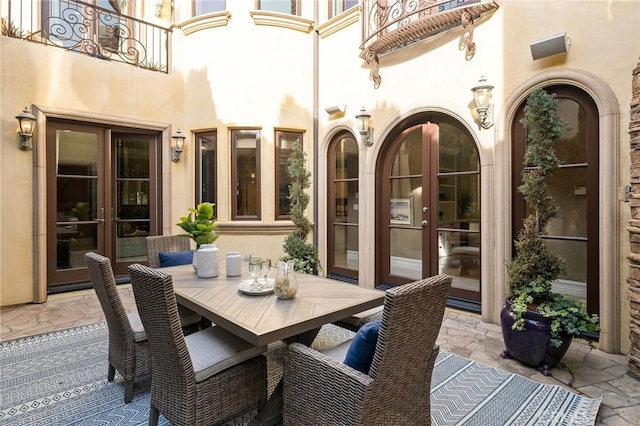 view of patio / terrace with a balcony, outdoor dining space, and french doors