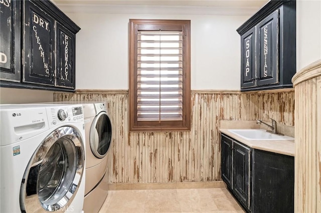 washroom featuring wainscoting, a sink, cabinet space, and washer and dryer