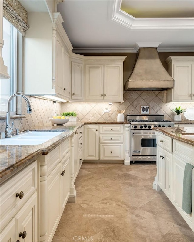 kitchen with premium range hood, premium stove, backsplash, and a sink