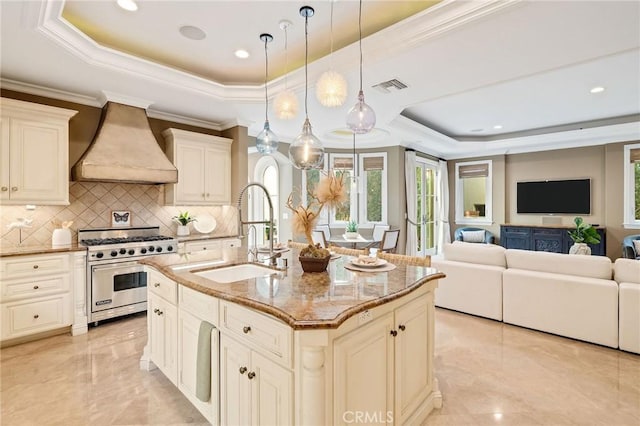 kitchen with premium range, a sink, visible vents, a tray ceiling, and custom range hood