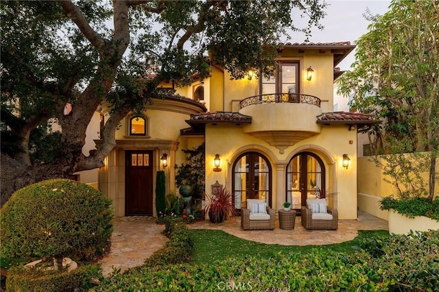 exterior space with french doors, stucco siding, fence, a balcony, and a tiled roof