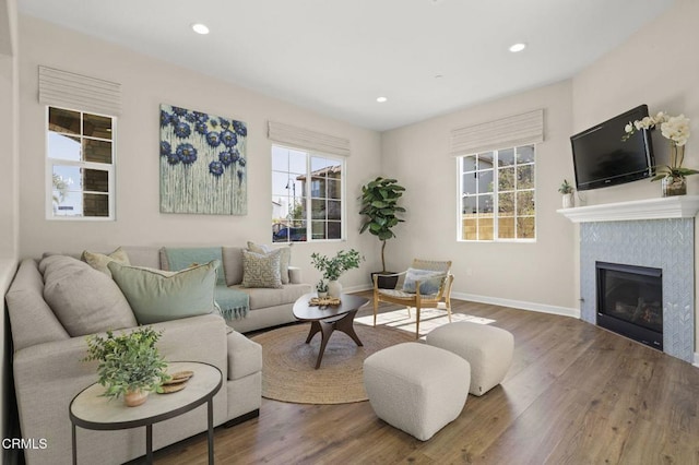 living room with a wealth of natural light, recessed lighting, wood finished floors, and a glass covered fireplace