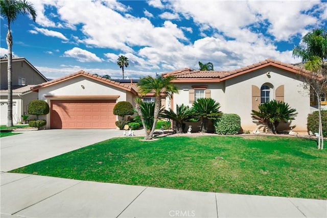 mediterranean / spanish-style home featuring solar panels, stucco siding, an attached garage, driveway, and a front lawn