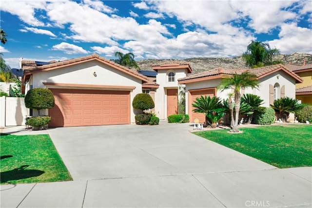 mediterranean / spanish house featuring a garage, driveway, a front lawn, and stucco siding