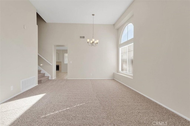 spare room featuring a chandelier, light colored carpet, visible vents, and stairway