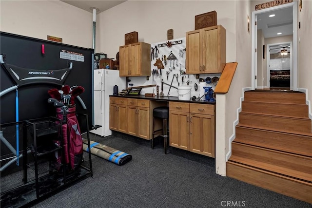 kitchen featuring decorative backsplash, dark countertops, ceiling fan, freestanding refrigerator, and dark carpet