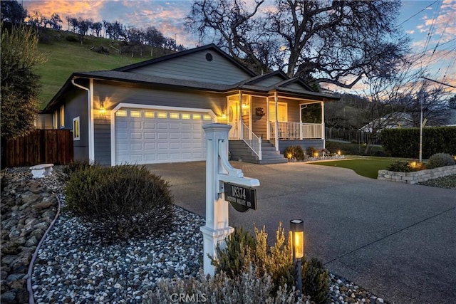 view of front of home featuring a garage, covered porch, fence, and concrete driveway