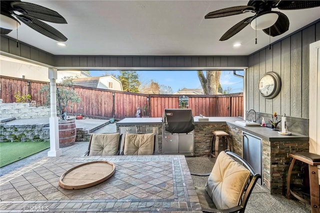 view of patio / terrace with a fenced backyard, ceiling fan, a sink, and area for grilling