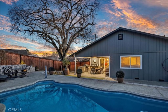 pool at dusk featuring a fenced in pool, outdoor dining area, a fenced backyard, and a patio