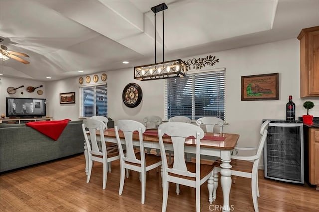 dining area featuring a bar, light wood finished floors, beverage cooler, and ceiling fan