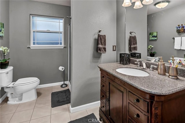 bathroom with a shower, toilet, vanity, baseboards, and tile patterned floors