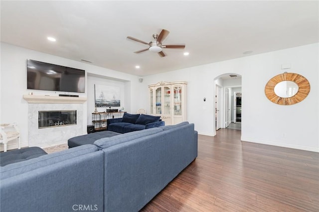 living room with arched walkways, recessed lighting, dark wood-type flooring, a fireplace, and baseboards