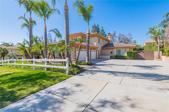 mediterranean / spanish home featuring driveway, a garage, a fenced front yard, a gate, and stucco siding