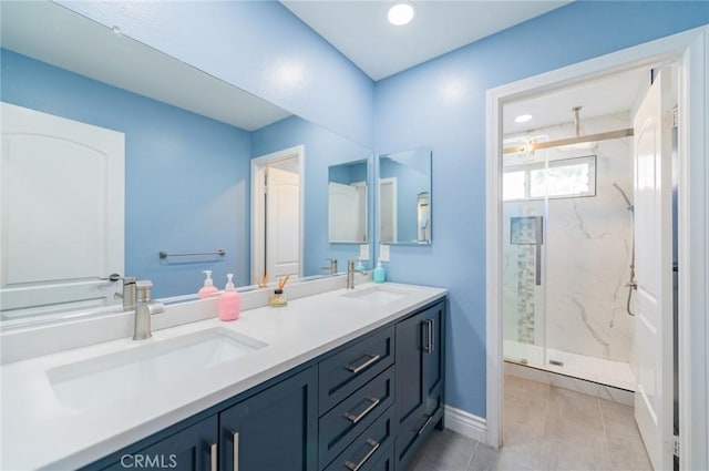 bathroom with baseboards, a sink, a marble finish shower, and double vanity