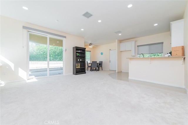 unfurnished living room with recessed lighting, visible vents, light carpet, ceiling fan, and baseboards