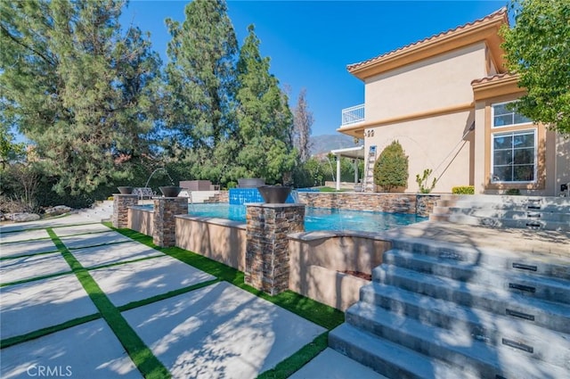 view of pool with an infinity pool, a patio, and area for grilling