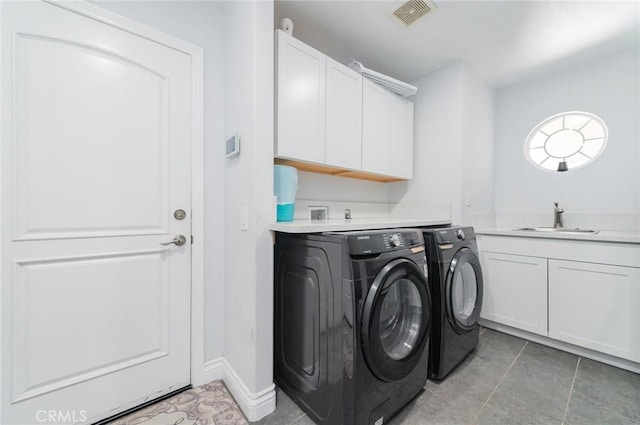 laundry area featuring cabinet space, visible vents, a sink, separate washer and dryer, and baseboards