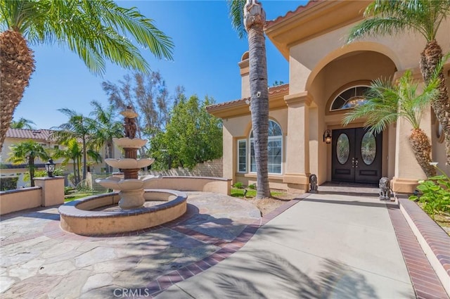 entrance to property with french doors, a tile roof, and stucco siding