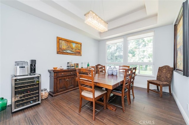 dining area with beverage cooler, a tray ceiling, dark wood-type flooring, and baseboards