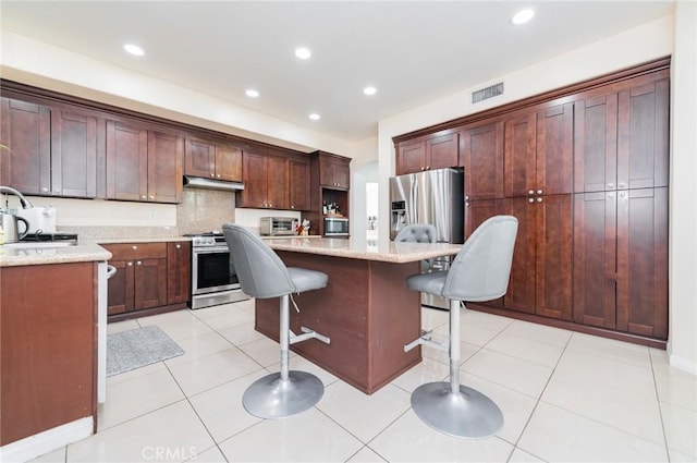 kitchen featuring a breakfast bar area, visible vents, appliances with stainless steel finishes, light tile patterned flooring, and a kitchen island