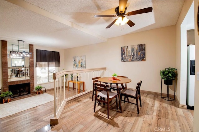 dining space with baseboards, a textured ceiling, light wood-style flooring, and a ceiling fan