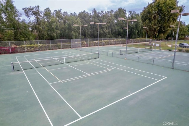 view of tennis court featuring community basketball court and fence