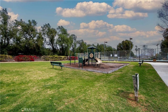 communal playground featuring fence and a lawn