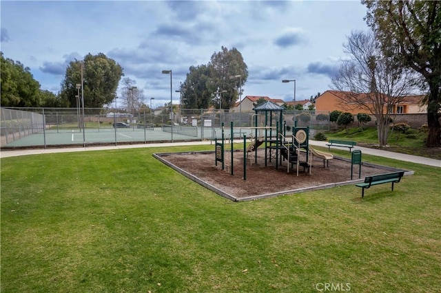 communal playground featuring a lawn and fence