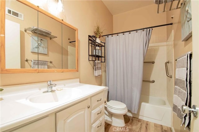 full bathroom featuring visible vents, shower / tub combo with curtain, toilet, wood finished floors, and vanity