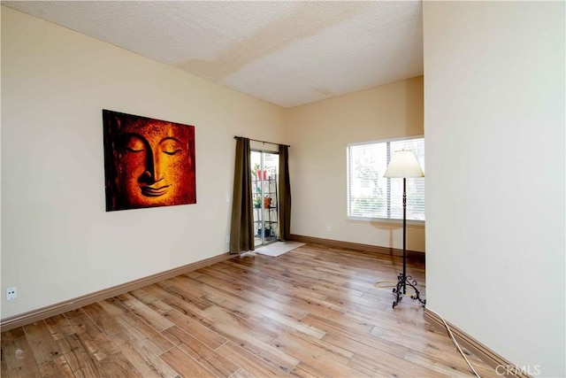 interior space with a textured ceiling, light wood-type flooring, and baseboards