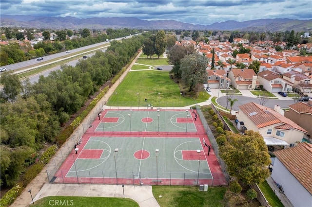 view of sport court featuring a residential view, community basketball court, a mountain view, and fence