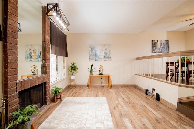 sitting room featuring a fireplace, wood finished floors, baseboards, and ceiling fan