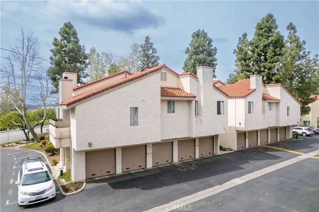 exterior space featuring stucco siding, a tiled roof, and a chimney