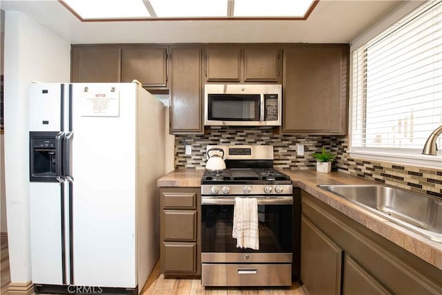 kitchen with decorative backsplash, light wood-style flooring, appliances with stainless steel finishes, and a sink