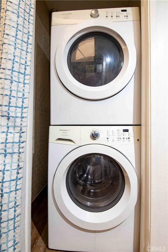 laundry room with laundry area, stacked washing maching and dryer, and wood finished floors