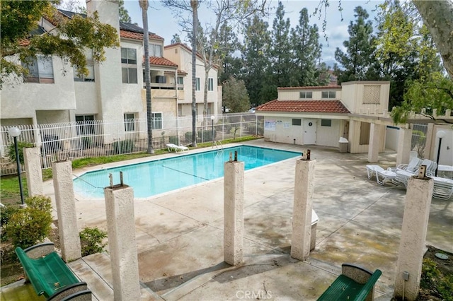 pool with a patio area and fence