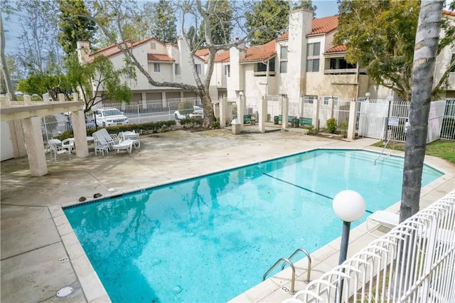 community pool featuring a patio, fence, and a residential view