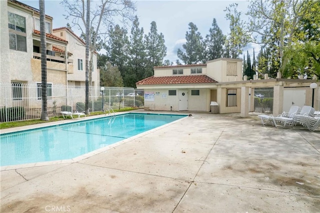 community pool with a patio and fence