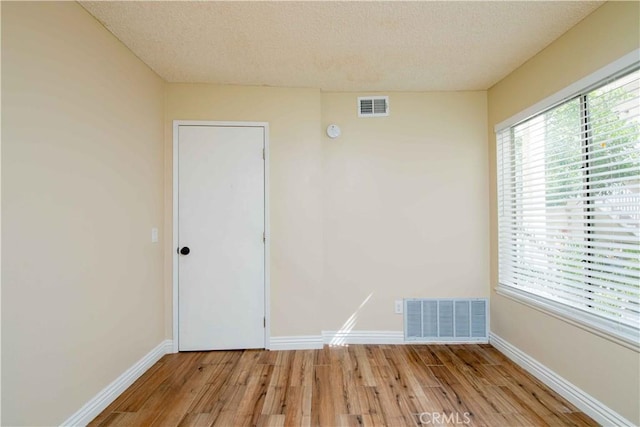 unfurnished room with visible vents, light wood-type flooring, and baseboards