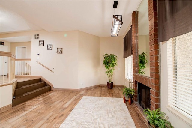 interior space with a brick fireplace, plenty of natural light, wood finished floors, and baseboards