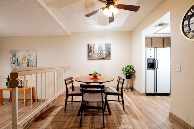 dining room with ceiling fan, visible vents, a textured ceiling, and light wood-style flooring