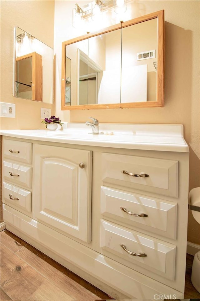 bathroom with vanity, toilet, wood finished floors, and visible vents